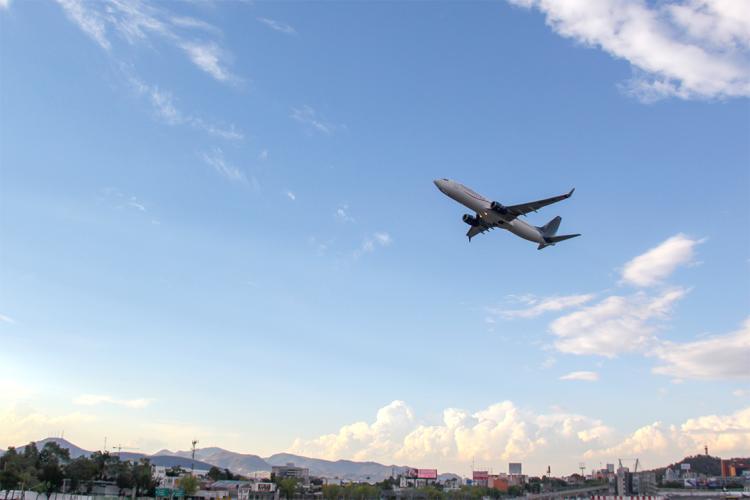 an airplane taking off with mountains and blue sky visible