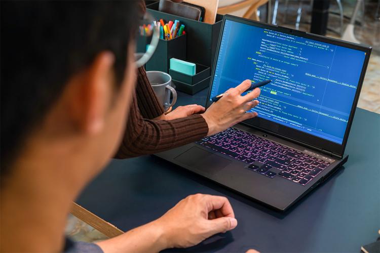 two people over a laptop with python programming language on the screen