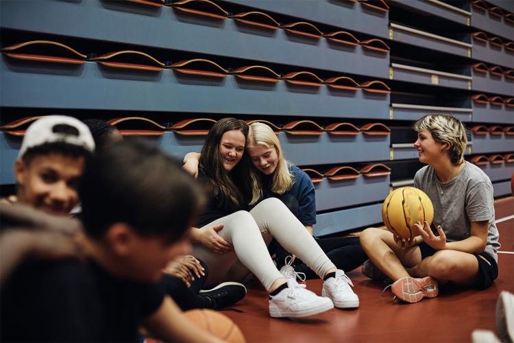 two girls laughing together with girl and boy basketball teammates