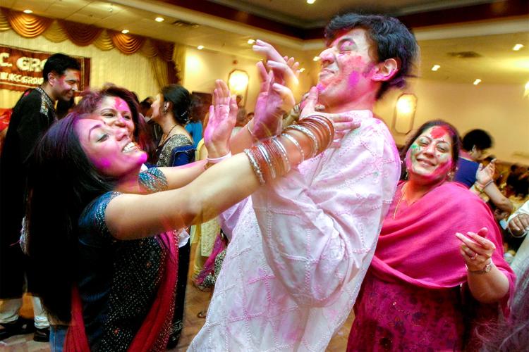 a woman rubs pink powder on a man during a party celebrating the holi Indian festival