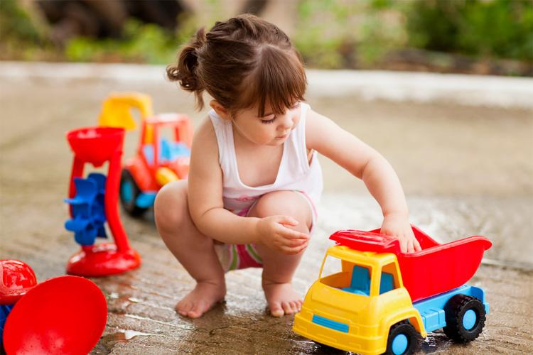 young girl playing with a toy truck