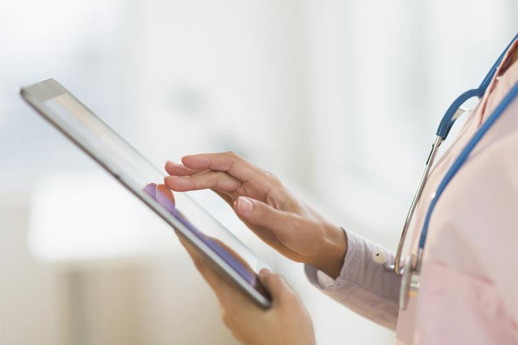 an anonymous female nurse holds an ipad