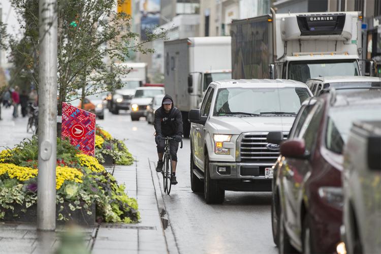 A man rides a bike along a busy Toronto street
