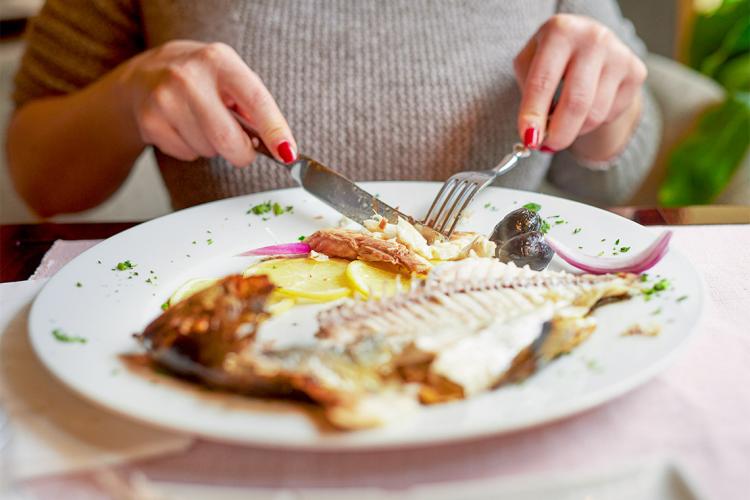 Woman eating fish in a restaurant