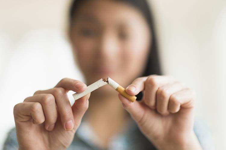 Asian woman breaking a cigarette in half
