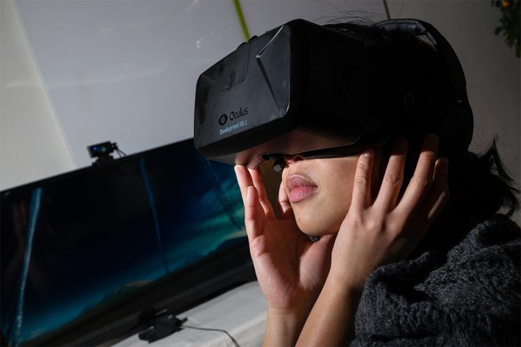 a southeast asian woman wears an oculus headset in a darkened room