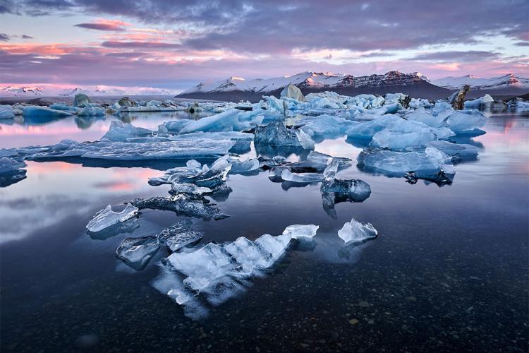 Sun sets over multiple small icebergs