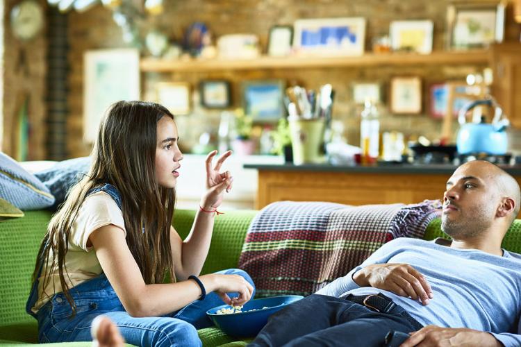 A father and daughter talking on a sofa