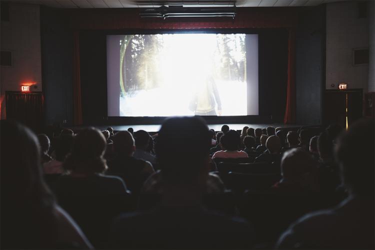 Stock photo of the backs of heads in a movie theatre