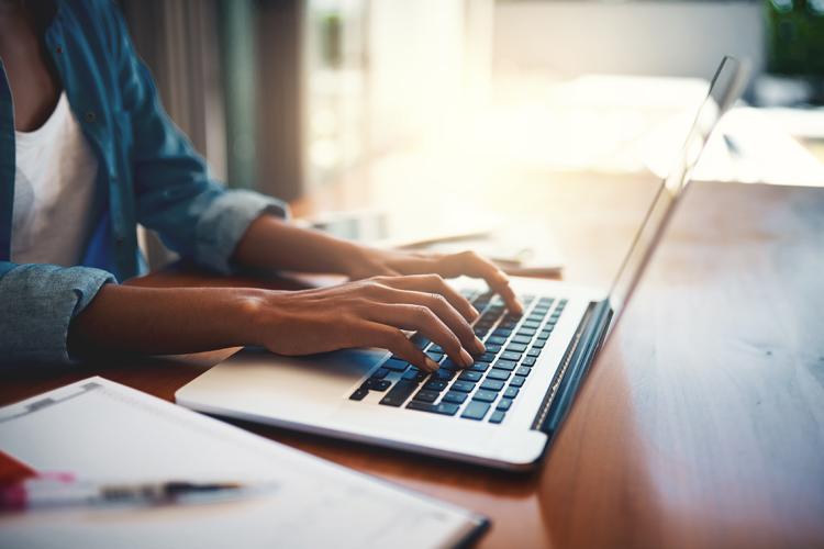 A woman types on a laptop