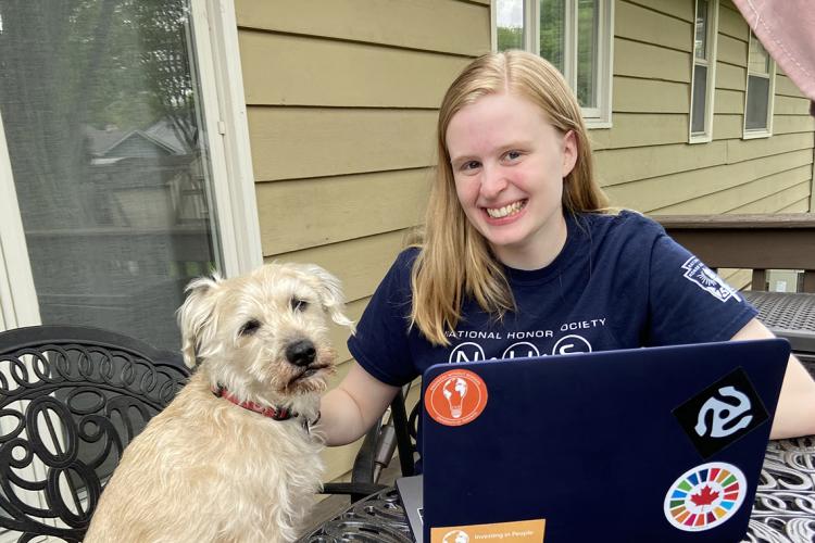 Photo of Lauren Streitmatter working on her computer at home, her dog by her side