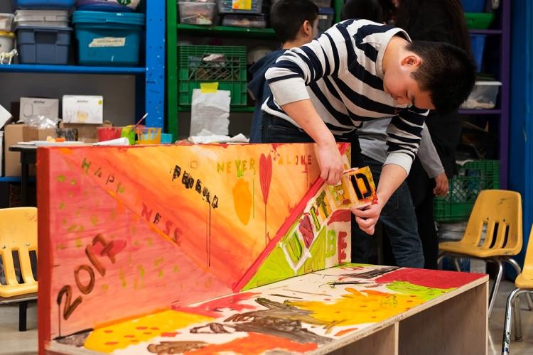 Student Josh Estrella stencilling on buddy bench at Art City 