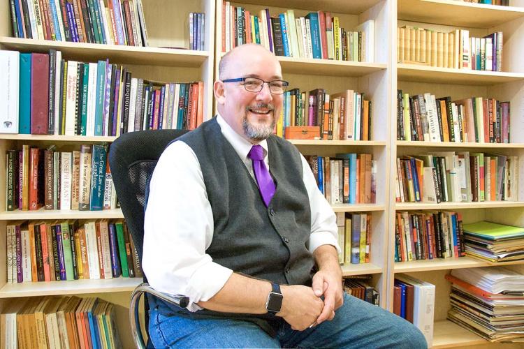 Portrait of Kevin White sitting in front of a bookcase