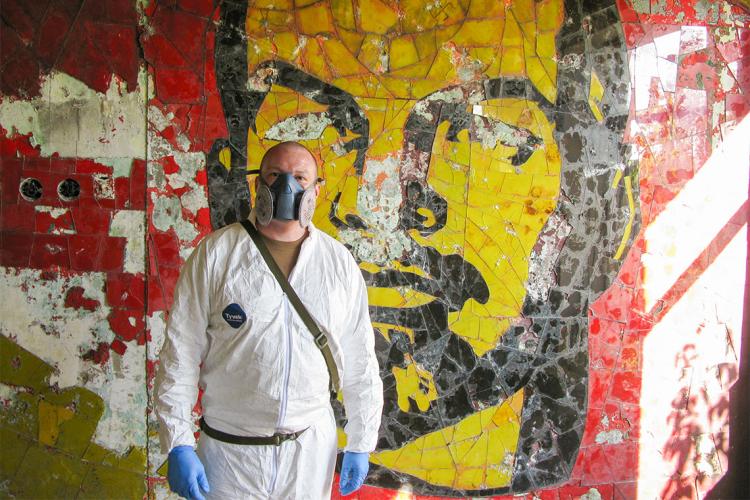 Gary Johnston in a tyvek suit in front of a graffti art rendition of Lenin
