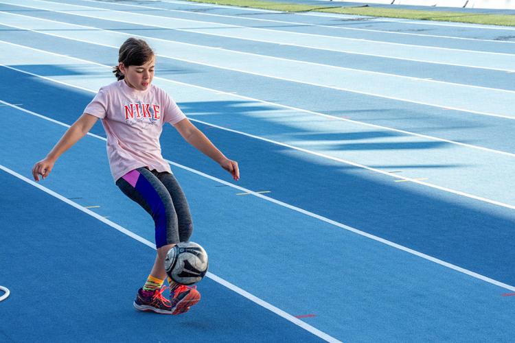 Young girl practices with a soccer ball at the university of toronto