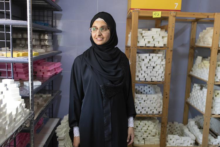 a Jordanian sitti soap employee stands in a storeroom surrounded by bars of soap
