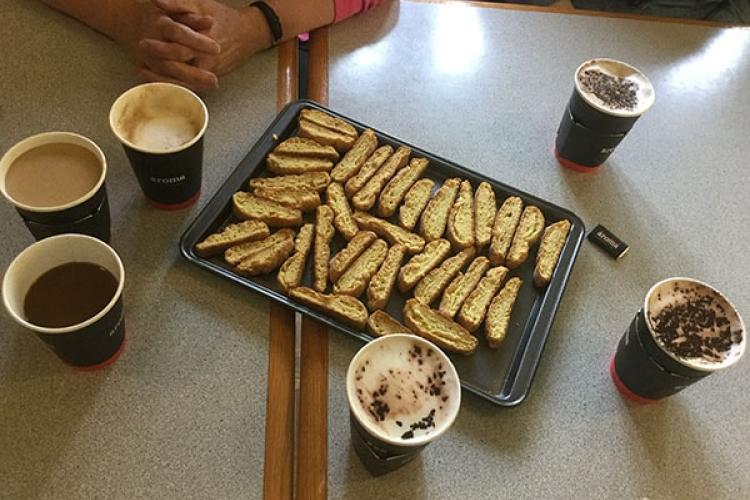 Biscotti on a tray, surrounded by paper cups of coffee