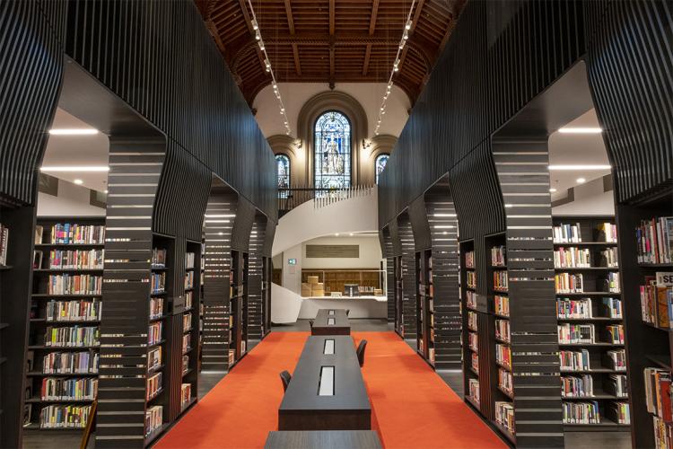 A view of the newly renovated library at University College with spiral staircase and stained glass window in the background