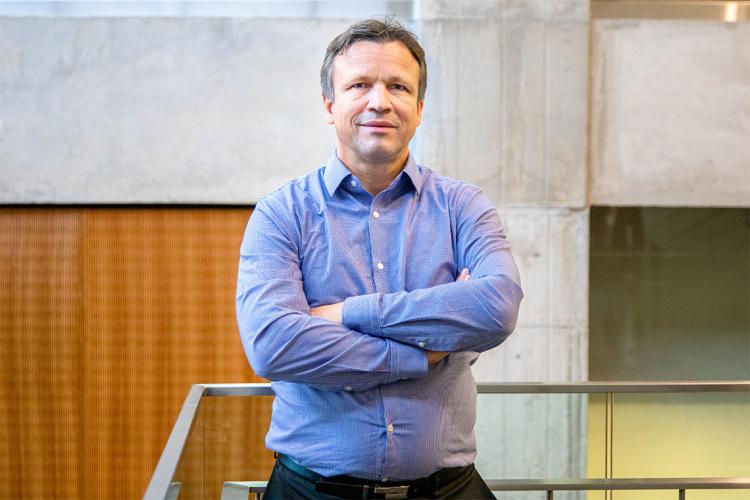 Professor Ulrich Schimmack of the University of Toronto Mississauga stands in front of a railing with his arms crossed