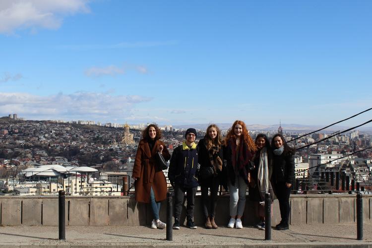 A group of students in the ICM program pose on a hilltop overlooking Tibilisi