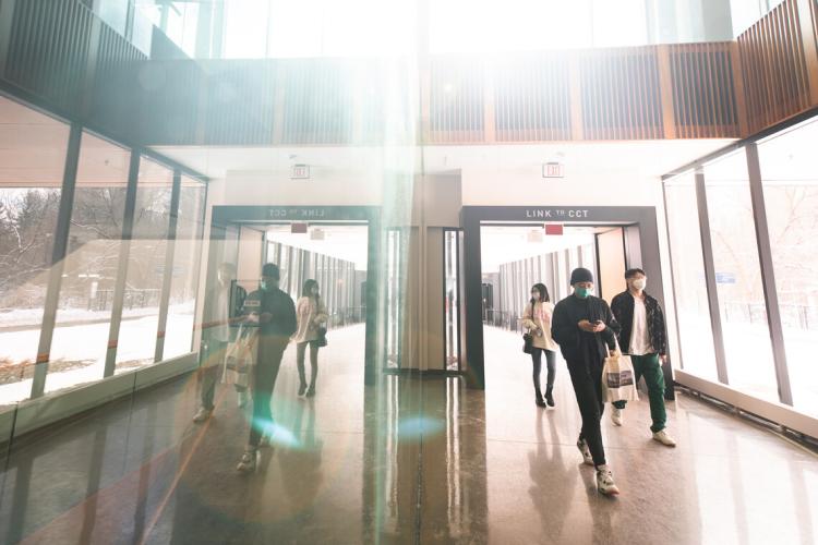 students walk down a sunny hallway at UTM