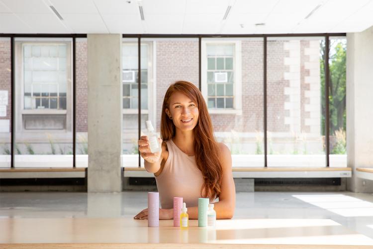 Portrait of Laura Burget holding up one of her fragrance products