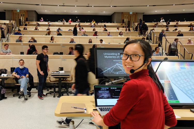Cherry Ng sits at the head of a lecture hall and is turned to the camera