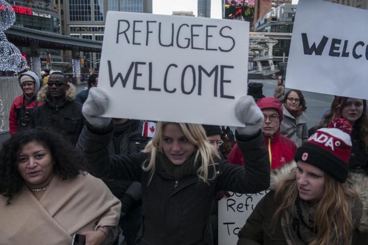 Woman holding a sign saying "Refugees Welcome" at rally in Toronto