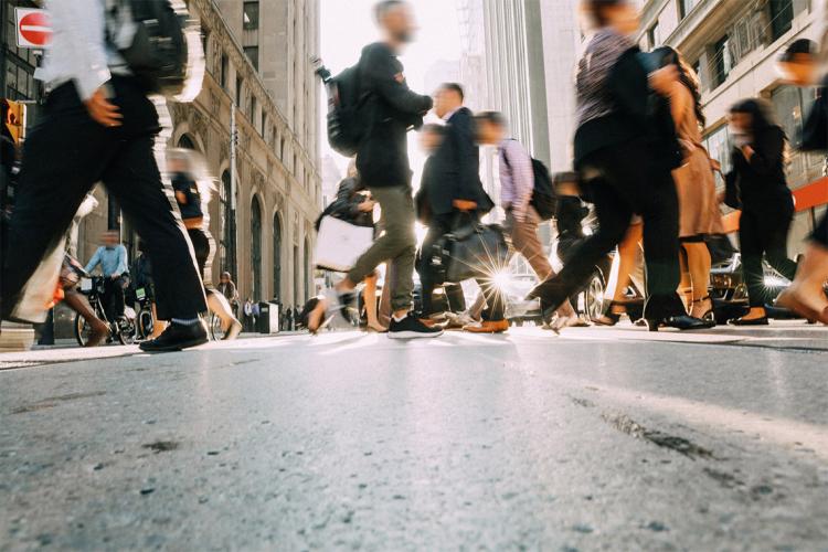 crowded downtown city street with many people walking across an intersection