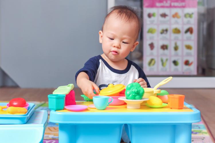 A young asian boy plays with colourful plastic toys