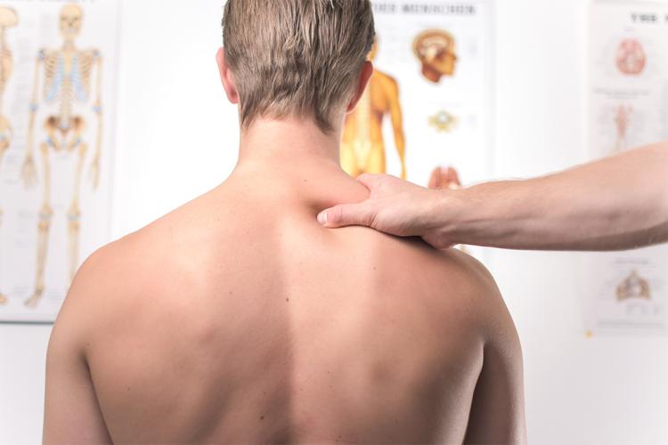 A teenager, with his back to the camera, receives treatment in a doctor's office