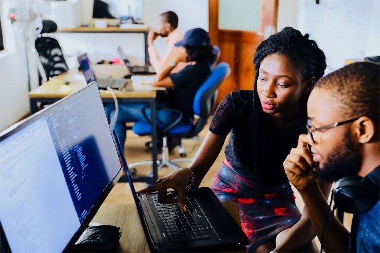 A Black woman and Black man work on a computer together