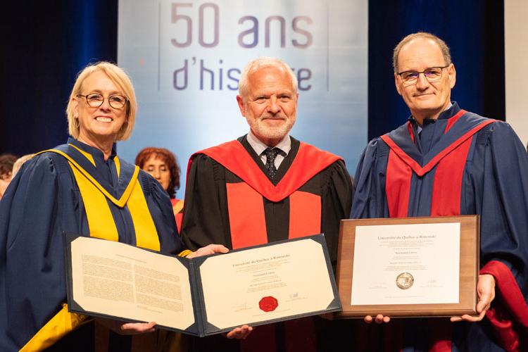 Photo of Professor Normand Labrie holding honorary degree, flanked by University of Quebec at Rimouski's president and rector