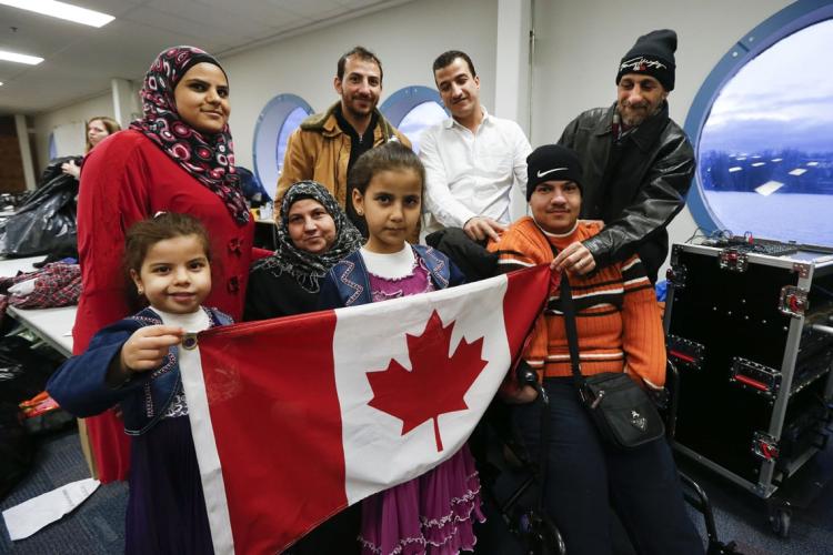 Syrian refugee family holding a Canadian flag