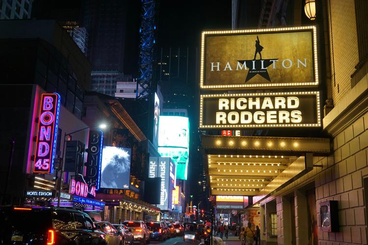 Broadway at night with a marquee for Hamilton in the foreground