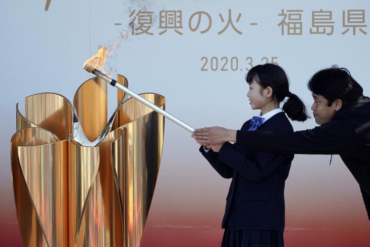 a man and a woman light an olympic cauldron together in tokyo