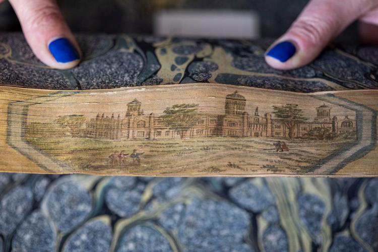 A fore-edge painting book's pages are fanned back to reveal an intricate illustration