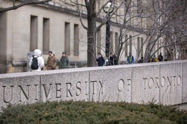 stone signage that reads "university of toronto" at the intersection of st. george st and college st in toronto