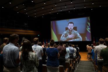 Zelenskyy puts is hand to his heart on screen while the crowd in Toronto gives him a standing ovation