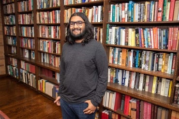 Portrait of incoming PhD student Seshu Iyengar shot in front of a row of bookshelves