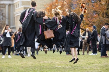 graduands jumping for joy in front of convocation hall