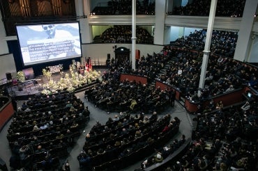 a wide view of the inside of a full convocation hall during the memorial