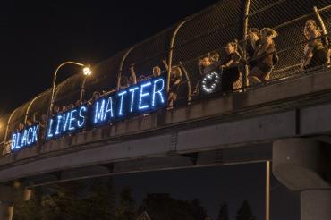 BLM supporters with a lit up Black Lives Matter sign on a bridge in Milwaukee 