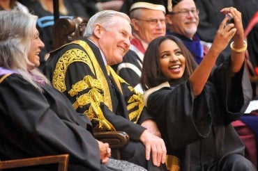 photo of graduating student taking selfie with chancellor