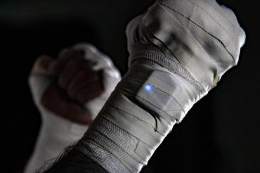 Photo of hands bandaged in fighting ready stance with wrist-mounted sensor