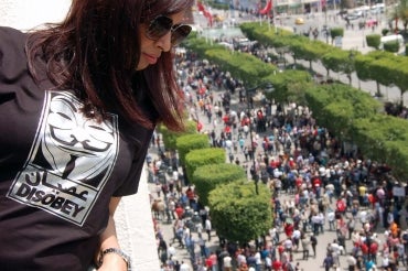 photo of woman on balcony overlooking protests in street below