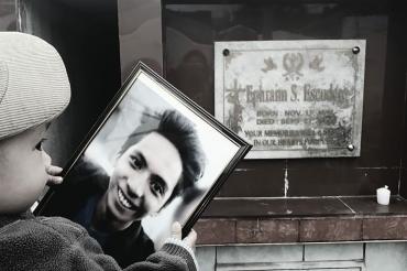 Photo of child holding father's picture near memorial