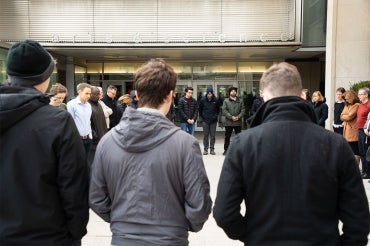 Students stand in a circle observing a moment of silence