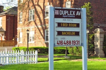 A wooden sign advertises apartments for rent in Toronto on Duplex avenue