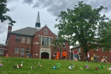 Children's shoes are placed on the ground in front of the Kamloops Residential School